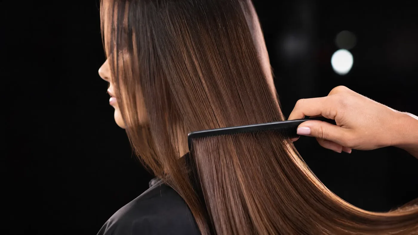 Prevent hair breakage — stylist combing healthy shiny hair at Monaco Salon Tampa